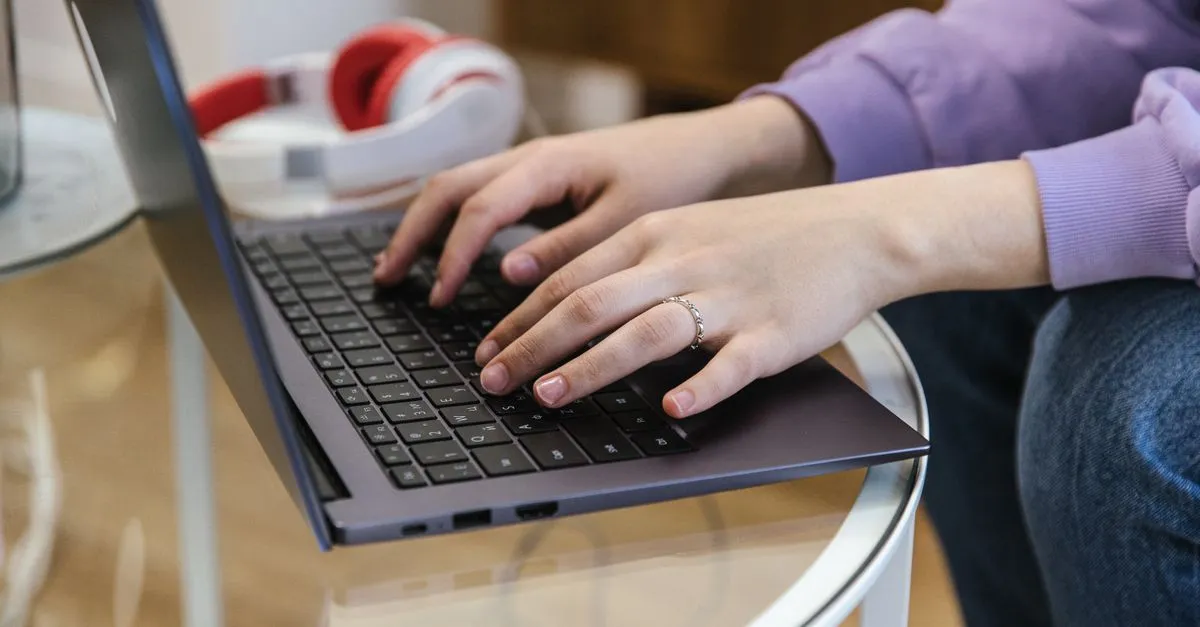 A person typing on a laptop at a desk, the everyday setting where phishing emails arrive