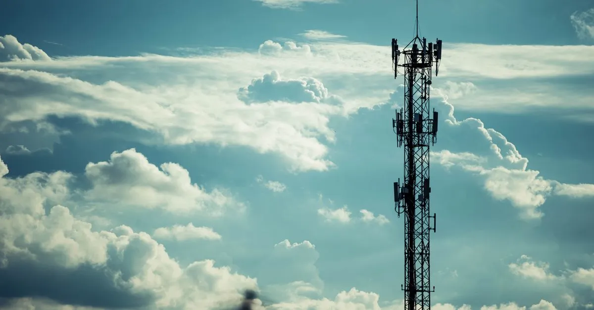 A wireless point-to-point dish mounted on a building exterior aimed across a field